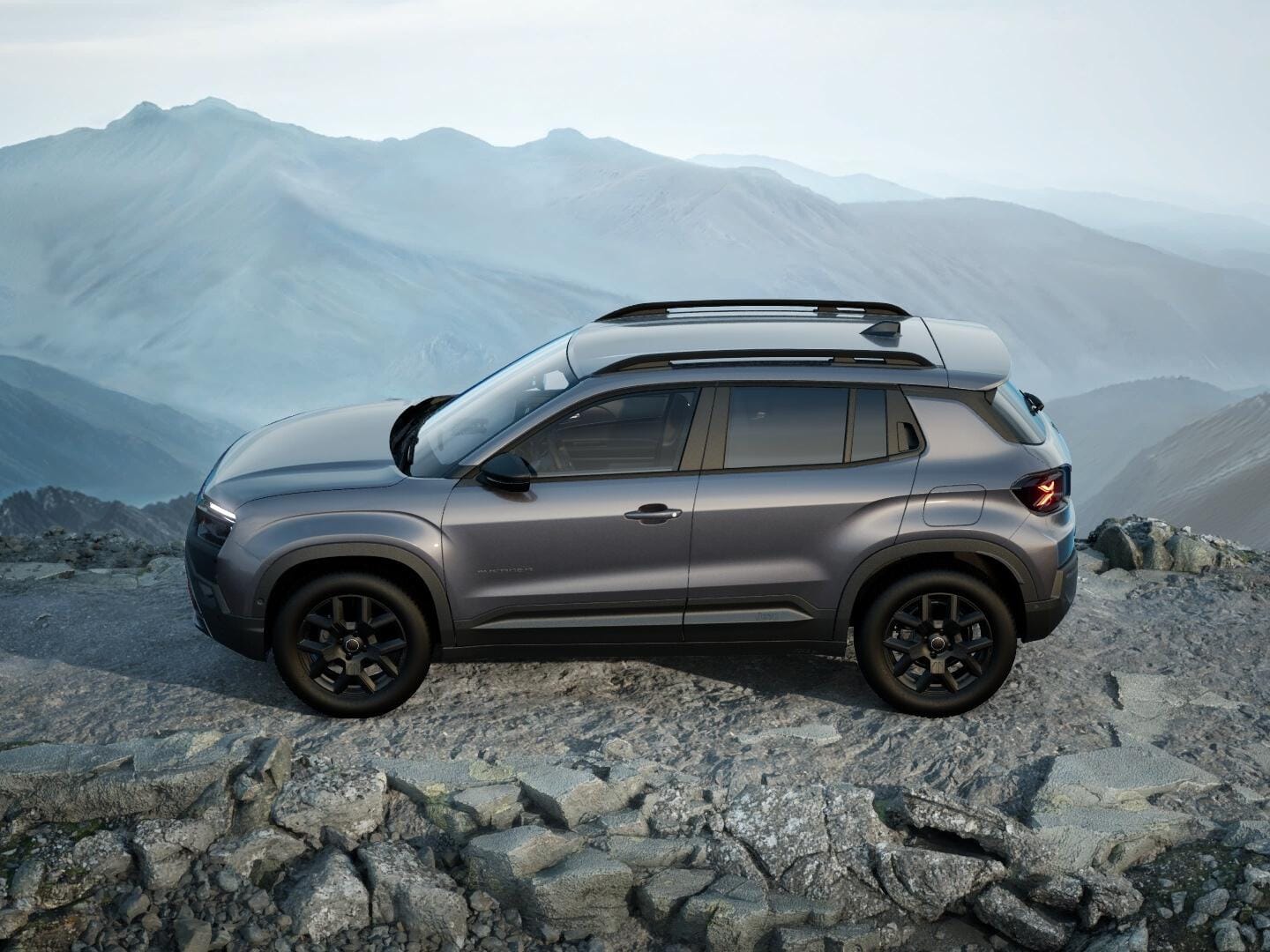 Grauer Jeep Avenger 4xe Upland in Seitenansicht auf felsigem Gelände in den Bergen.