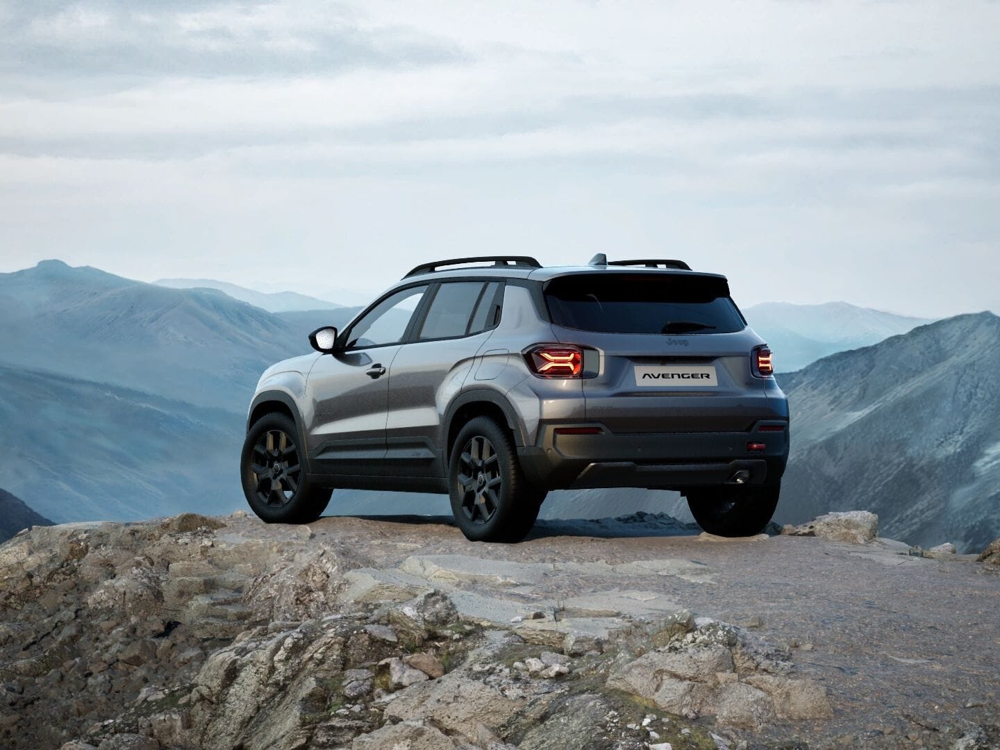 Grauer Jeep Avenger 4xe Upland in Heckansicht vor einer weitläufigen Berglandschaft.