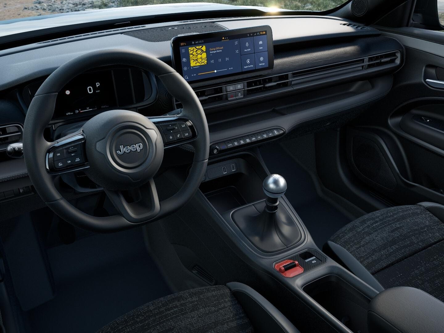 Innenraum des Jeep Avenger Longitude mit digitalem Cockpit, zentralem Touchscreen und manuellem Schalthebel.