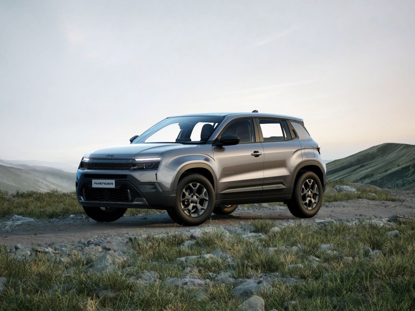 Grauer Jeep Avenger Longitude in Frontansicht vor einer weitläufigen Berglandschaft.