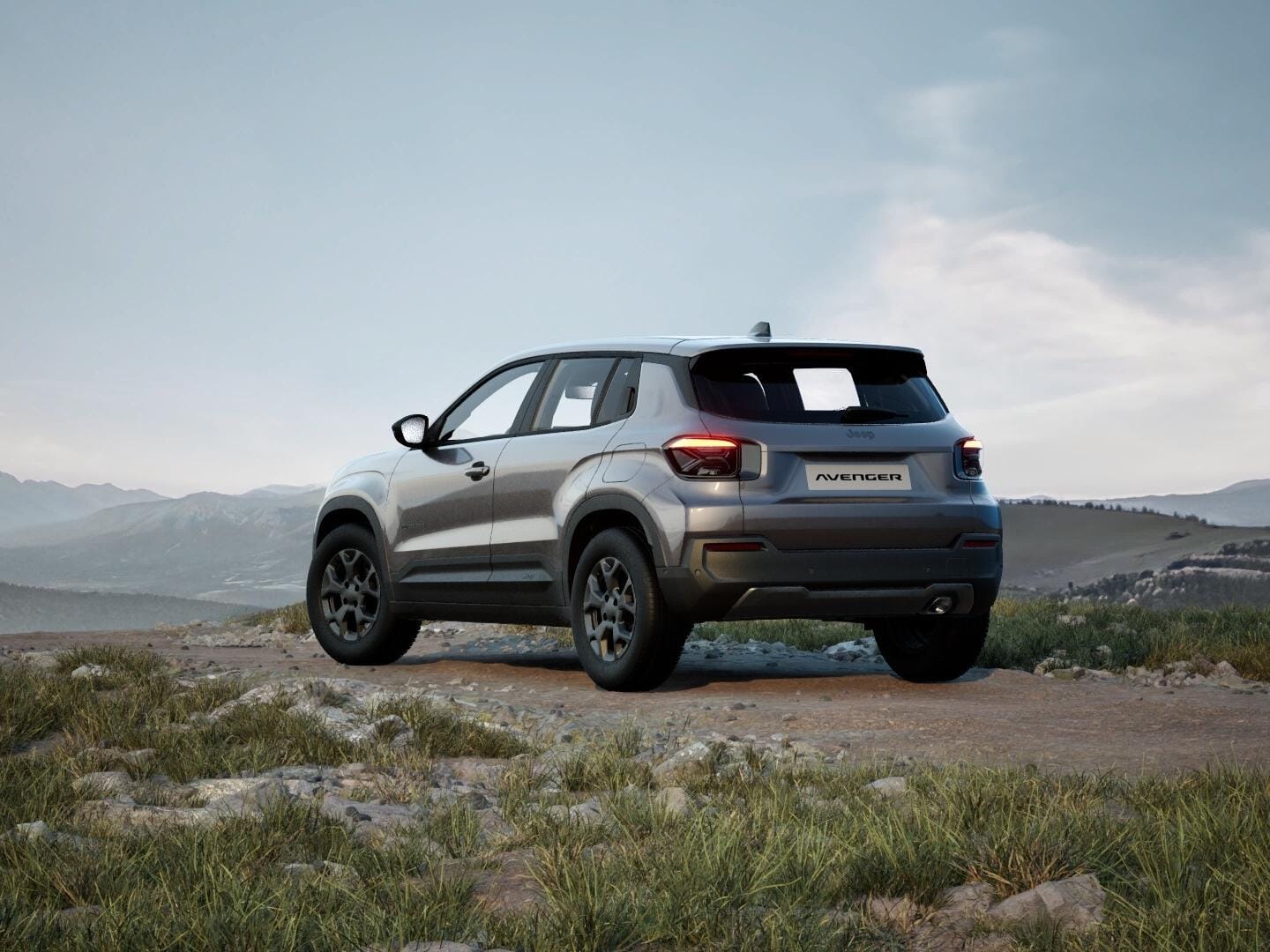 Grauer Jeep Avenger Longitude in Heckansicht vor einer weitläufigen Berglandschaft.